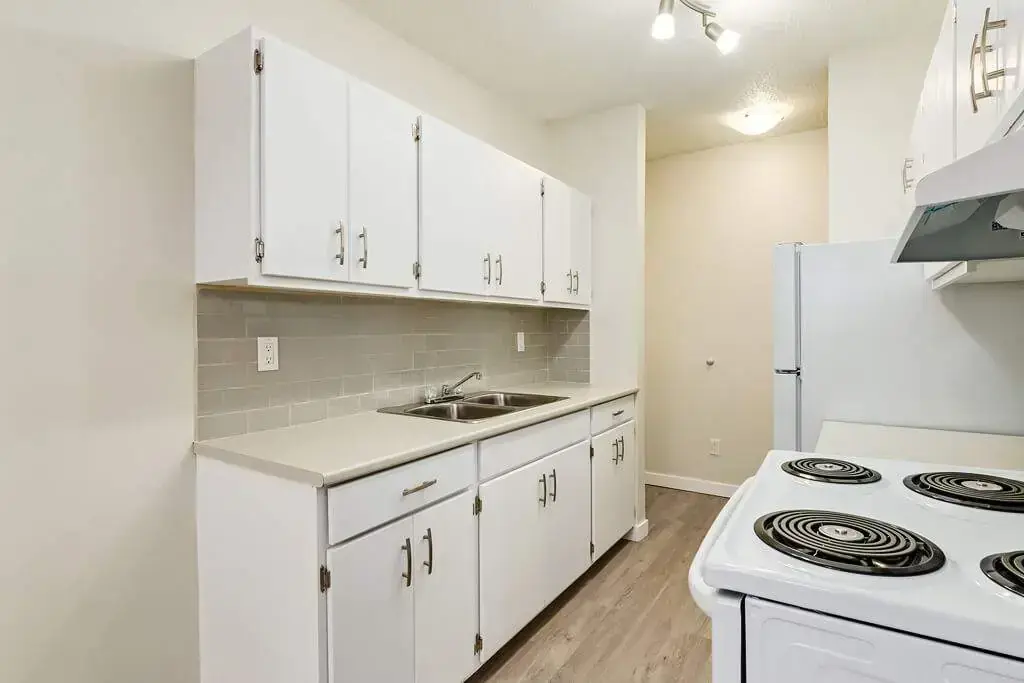 Galley style kitchen with fridge and stove at Hyland Manor in Bonnyville.
