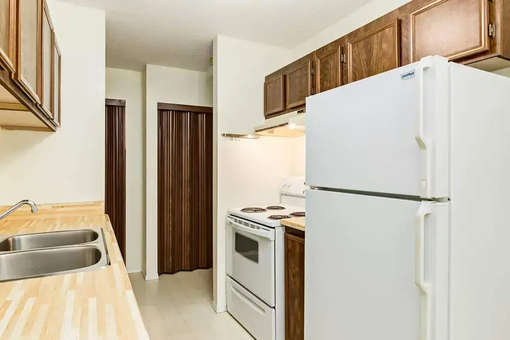 Galley style kitchen with fridge and stove at King Art in Bonnyville.