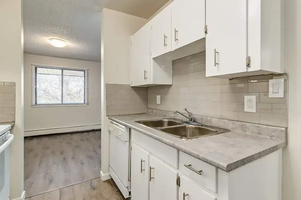 Galley style kitchen and sunlit dining area at Hudson Court in Edmonton.