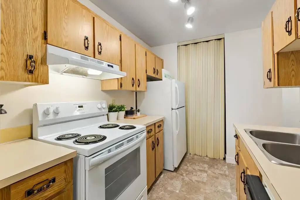 Galley style kitchen with fridge and stove at Hudson Court in Edmonton.