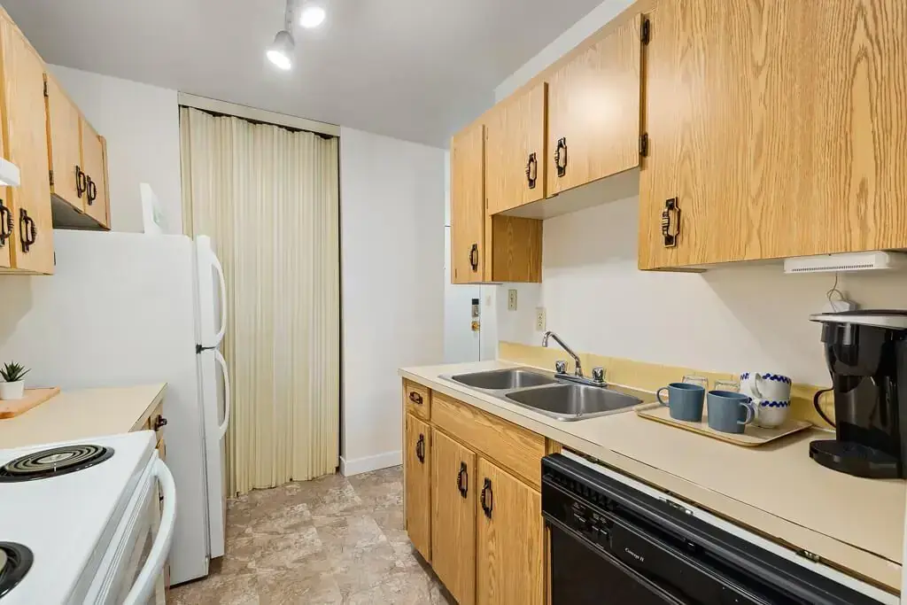 Galley style kitchen with fridge and stove at Hudson Court in Edmonton.