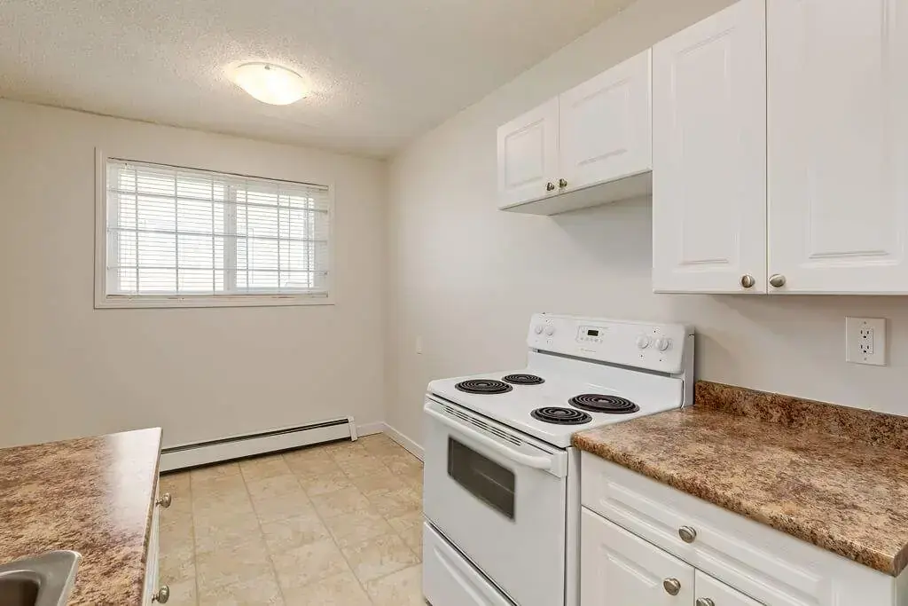 Galley style kitchen with good size dining area with natural light at Lenita Manor in Edmonton.