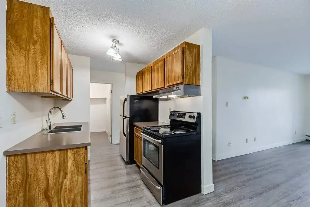 Galley style kitchen with fridge and stove at Chancellor Gate in Saskatoon.