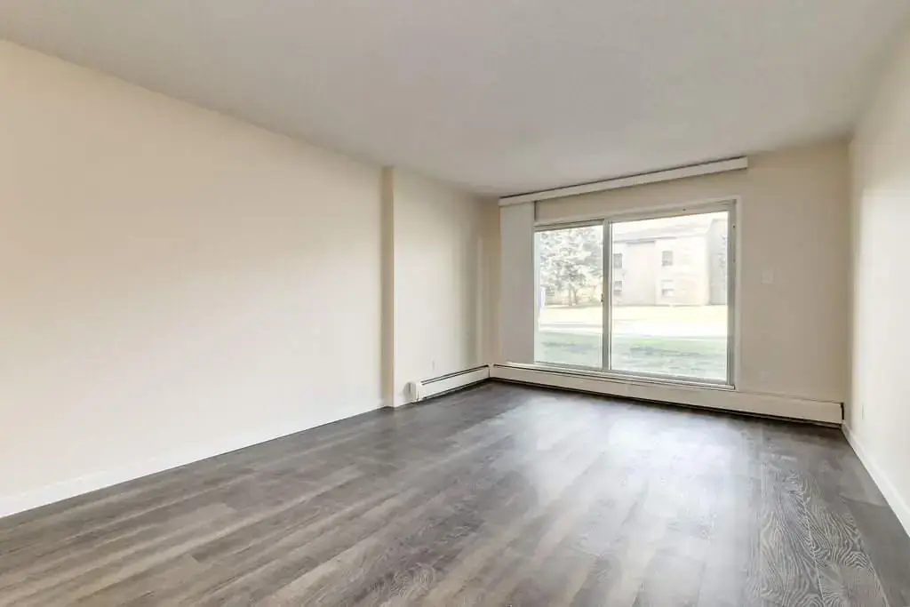 Sunlit living room with large windows at Westwind Apartments in Wetaskiwin.