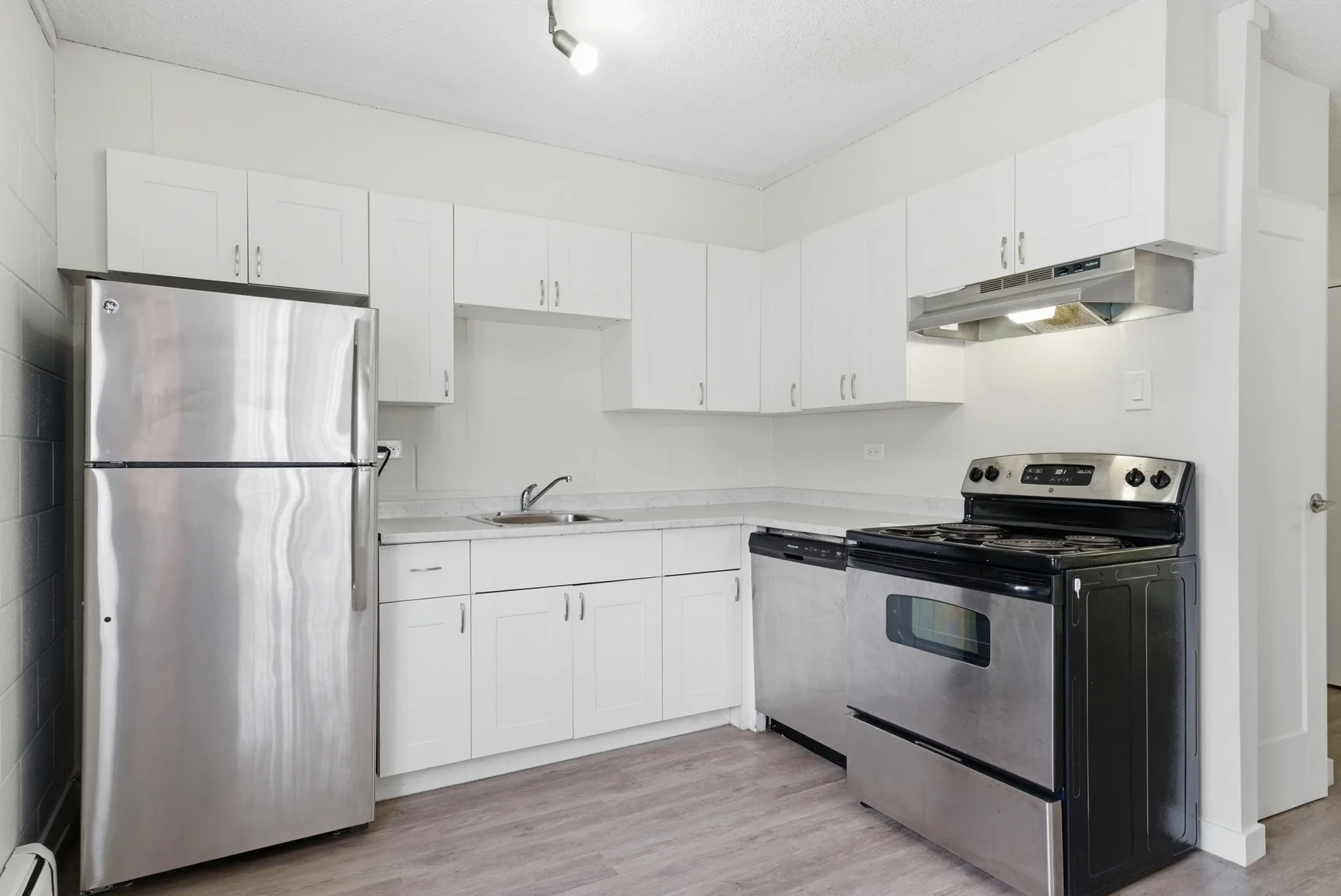 Well-appointed kitchen with stainless steel fridge and stove at Miami Apartments in Saskatoon.