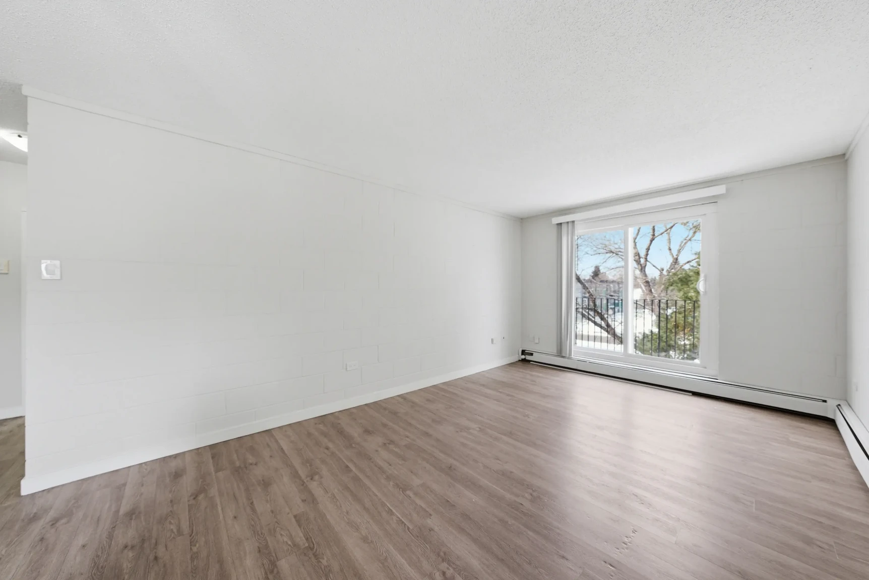 Bright living room with large windows at Miami Apartments in Saskatoon.