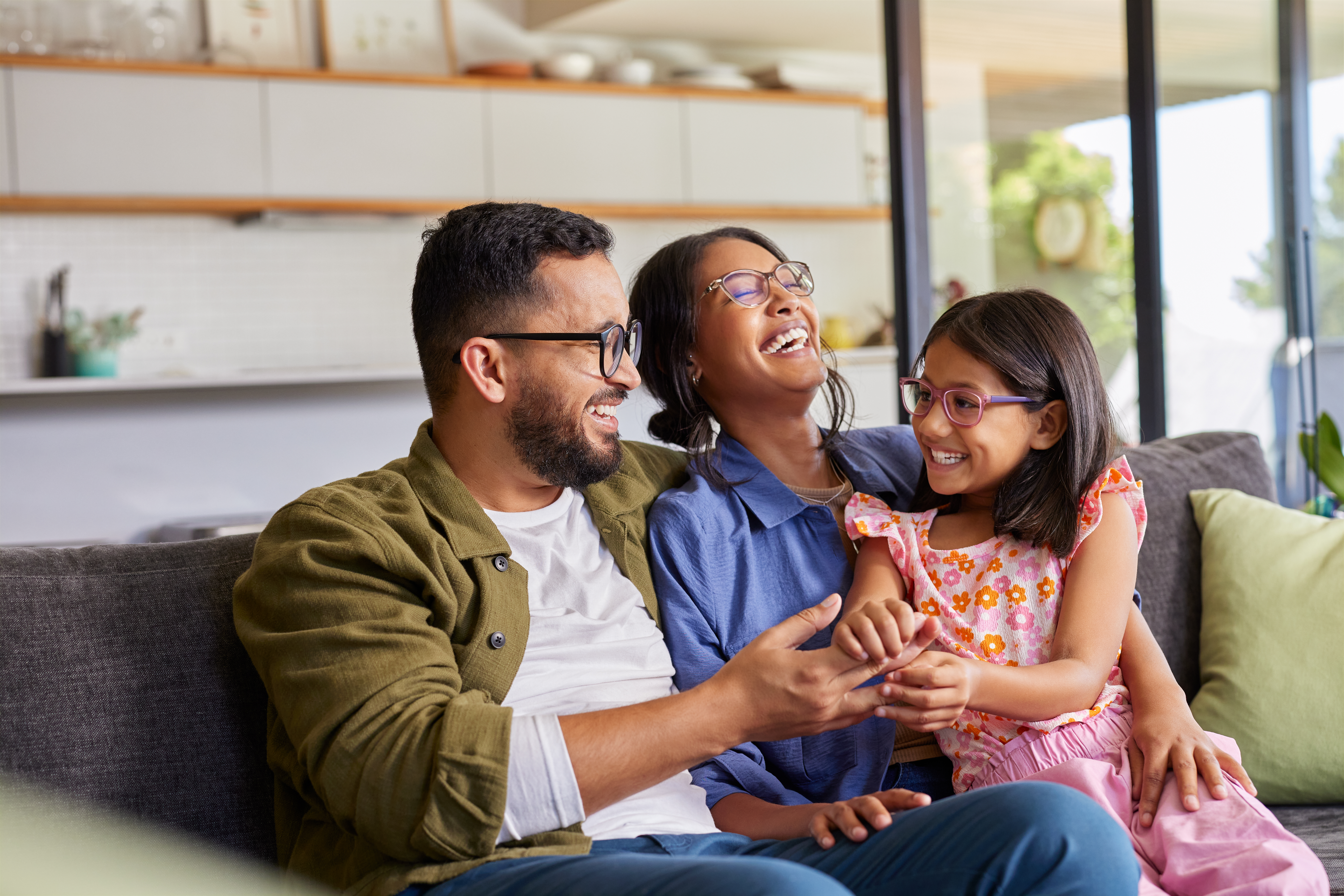 Image of family sitting on a couch and laughing. 