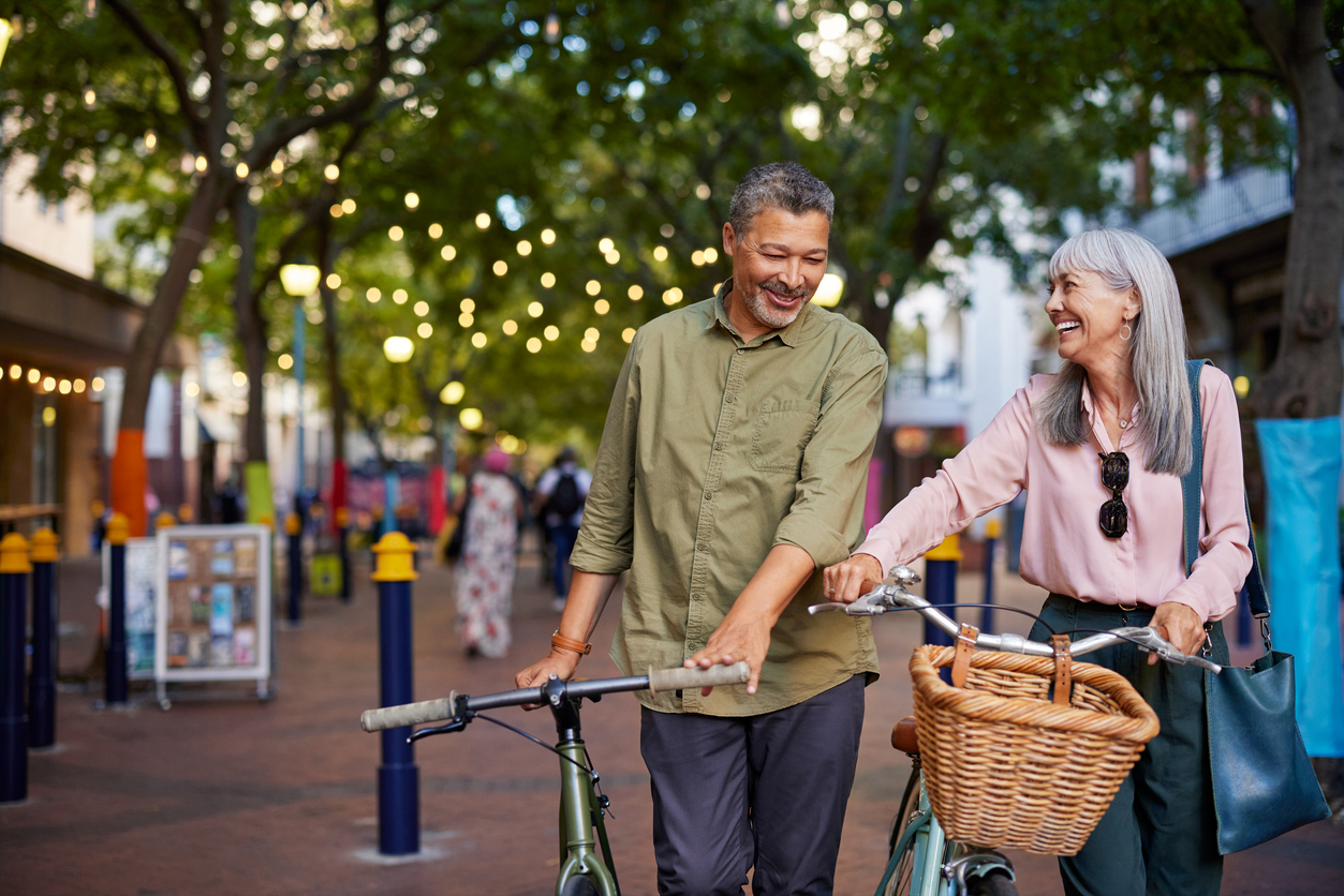 Image of couple with bicycles surrounded by trees and shops.