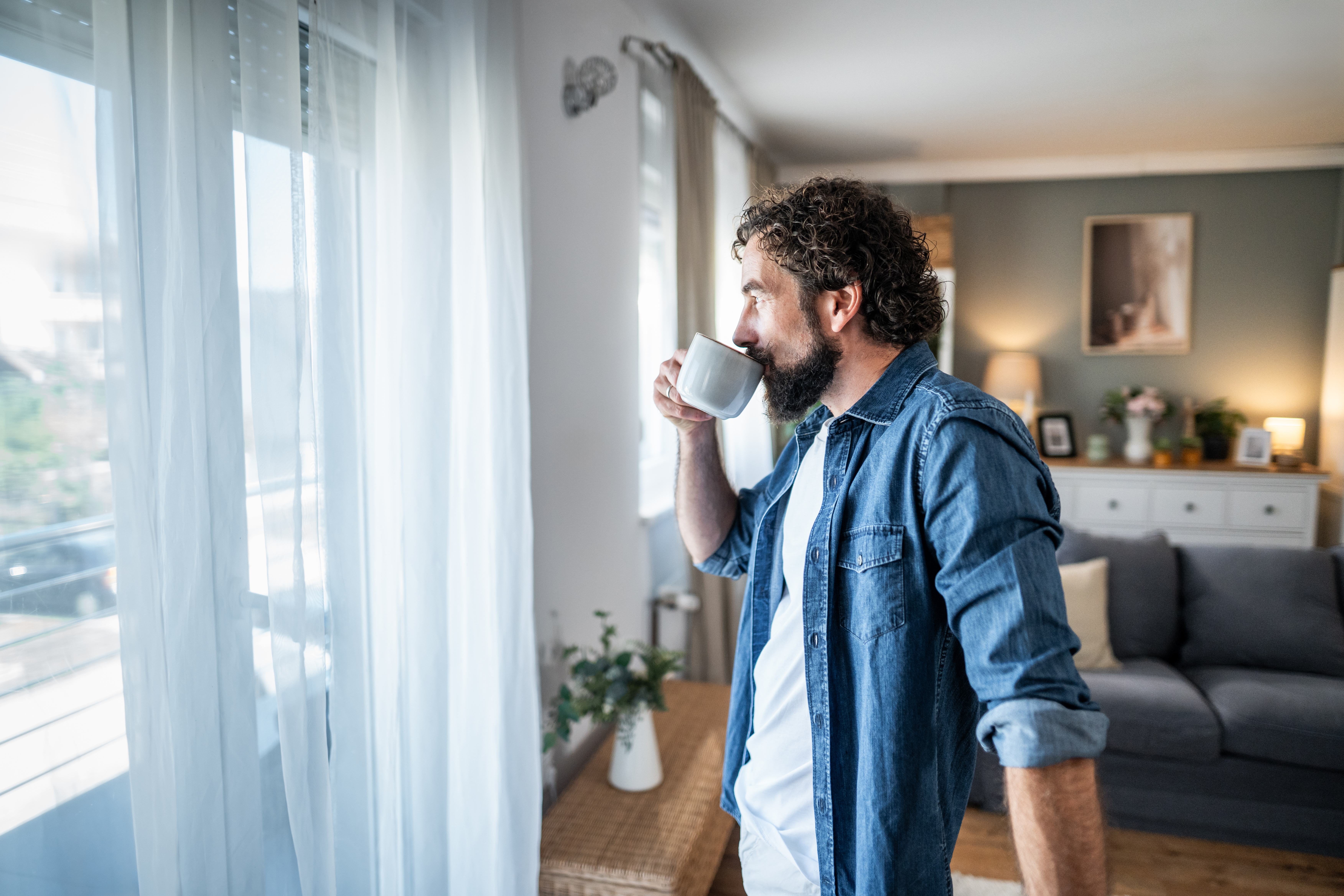 Image of man sipping coffee inside his home.