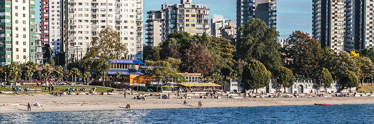 View from the water of English Bay Beach and the tall white Regency Park apartment building in Vancouver's West End.