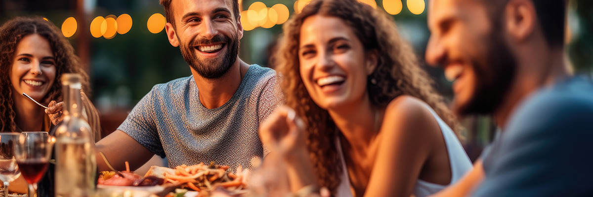 Friends enjoying a lively outdoor evening meal at a local restaurant patio in the West End of Vancouver.