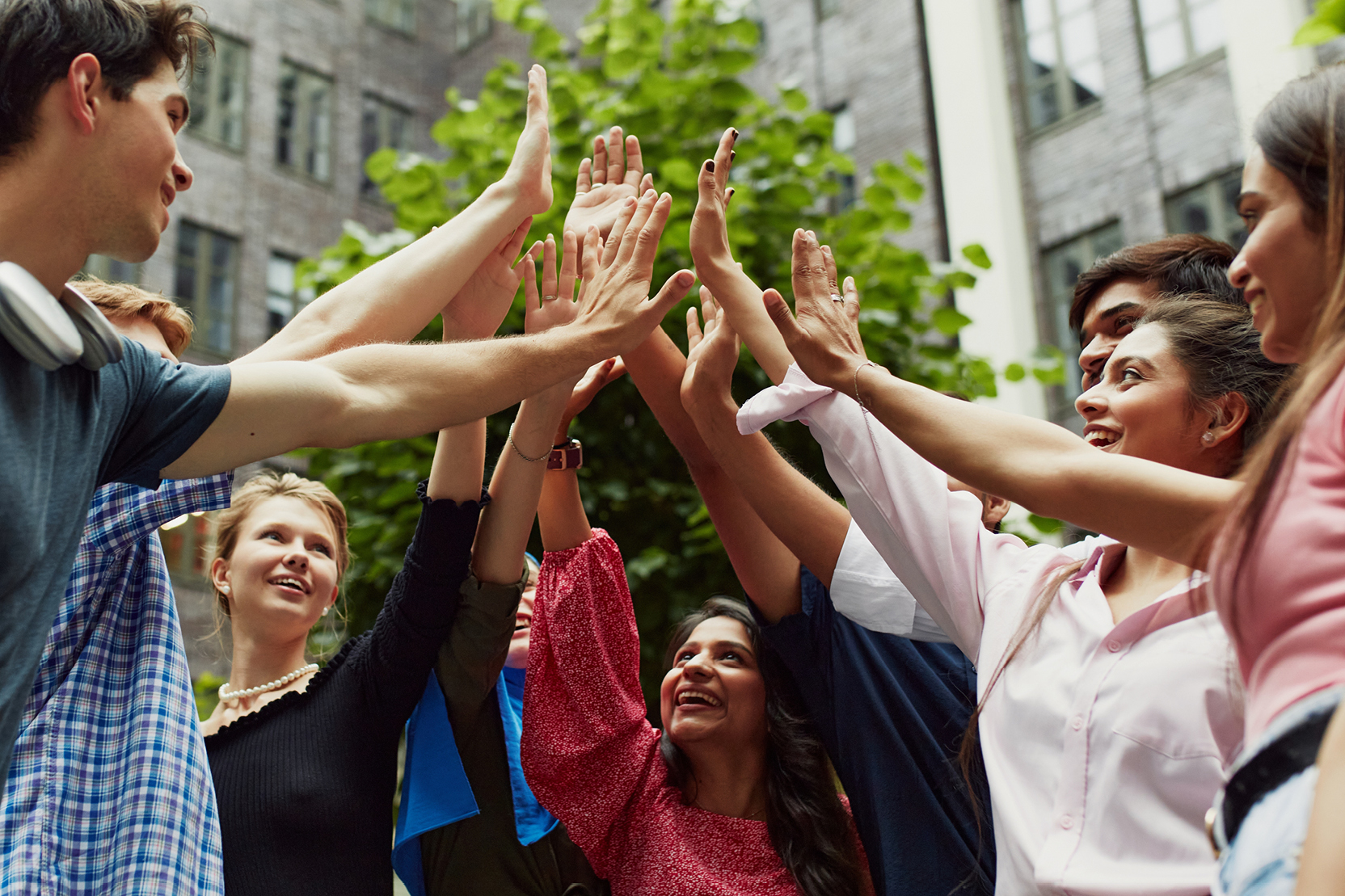 Group of students doing a group high-five outdoors.