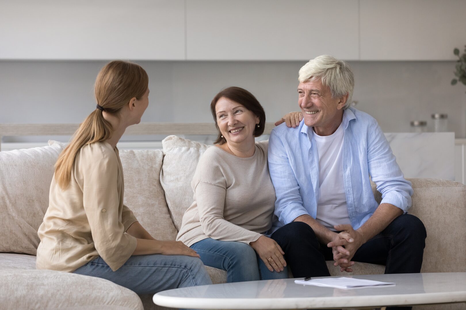 Young woman meeting with a smiling older couple in a modern apartment living room