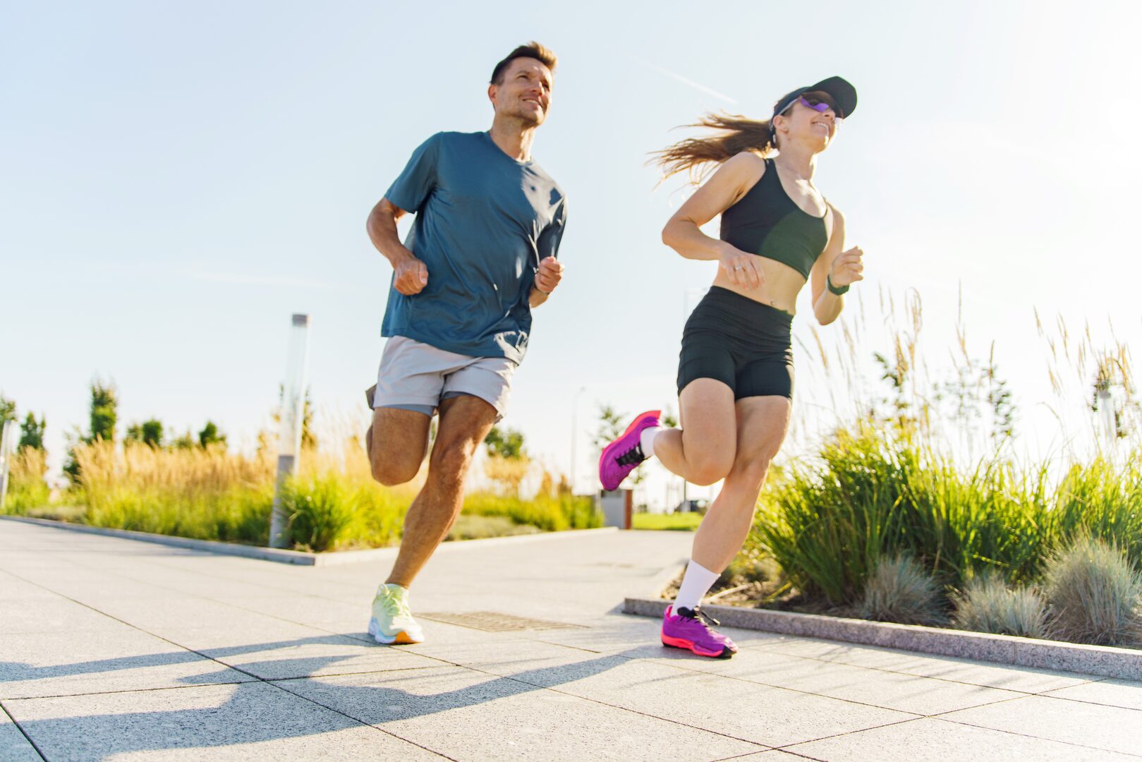 Man and woman jogging together outdoors on a sunny day in an urban park setting