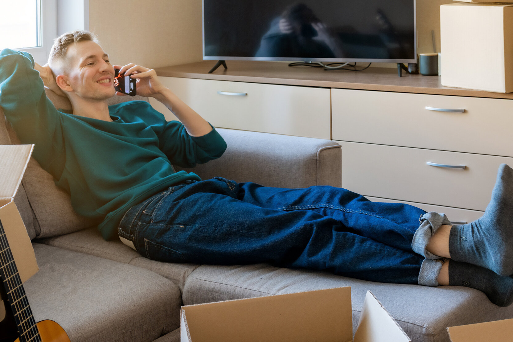 Young man relaxing on a couch amid moving boxes