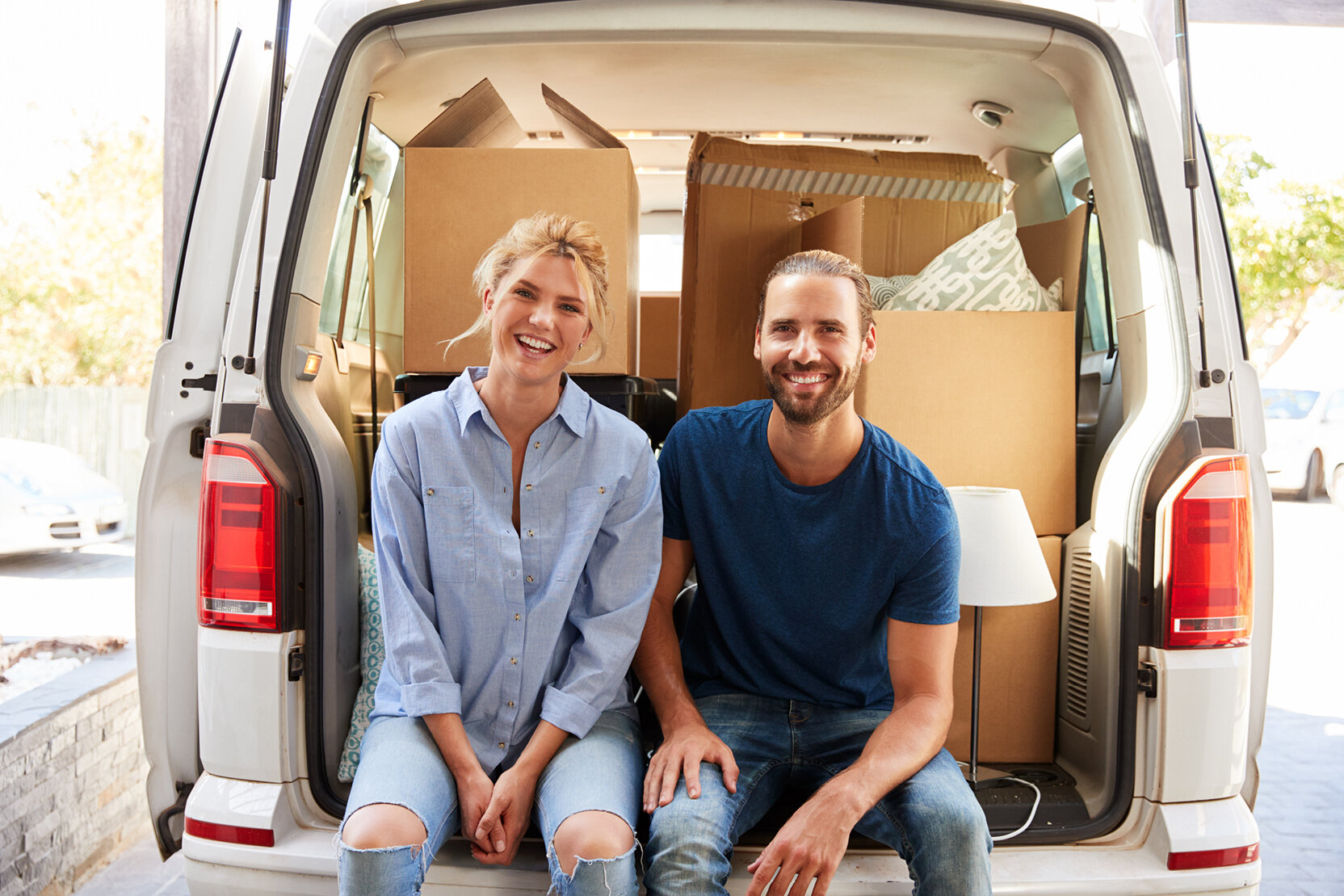 Smiling couple sitting in the back of a loaded moving van