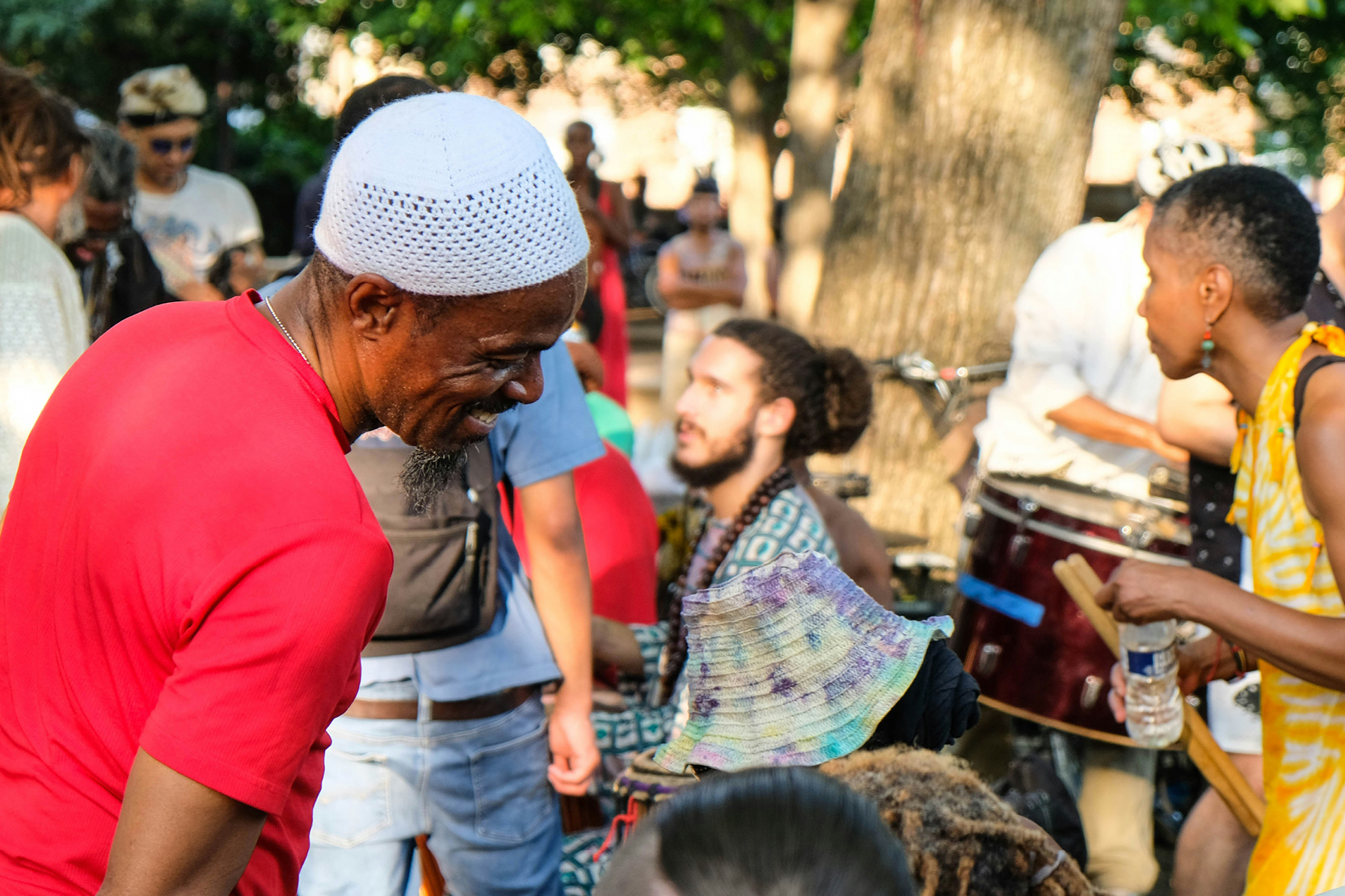 Man smiling while drummers play at an outdoor cultural gathering