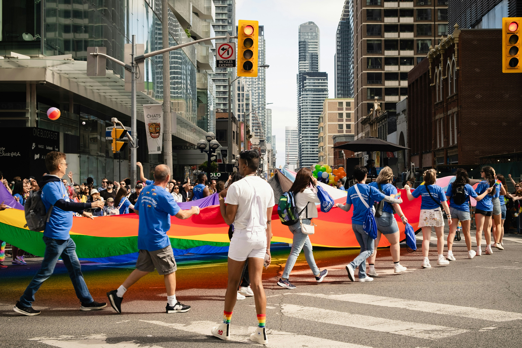Participants carrying a large rainbow flag through downtown Toronto at the Pride Parade