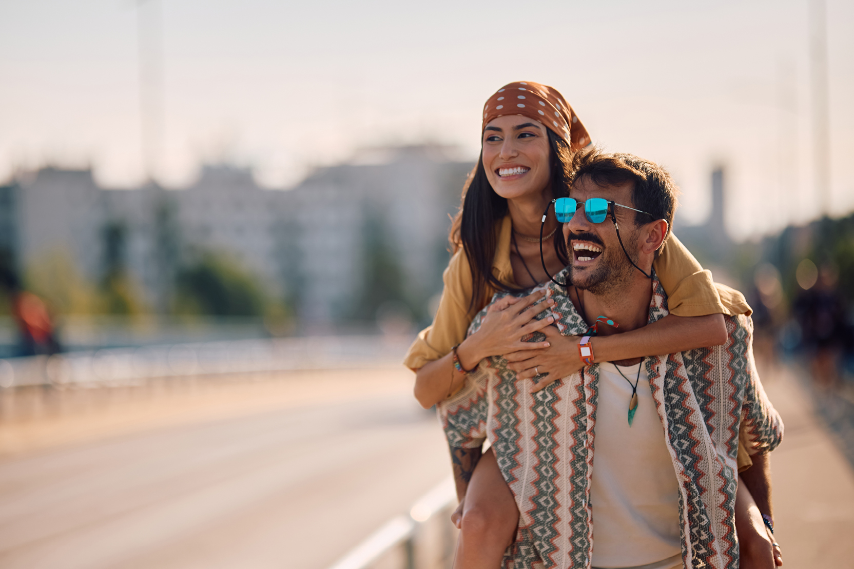 Man carrying a smiling woman on his back while walking along a path.