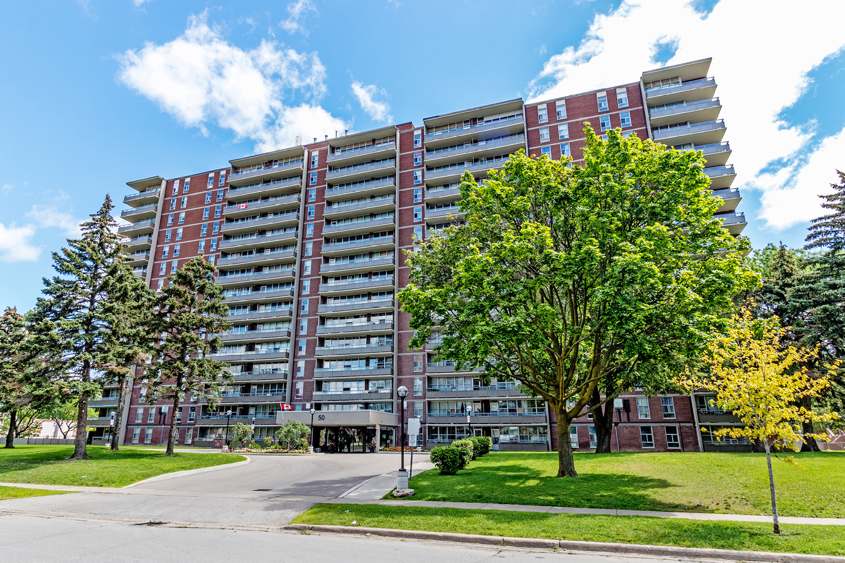 Apartment building surrounded by green lawns and mature trees.