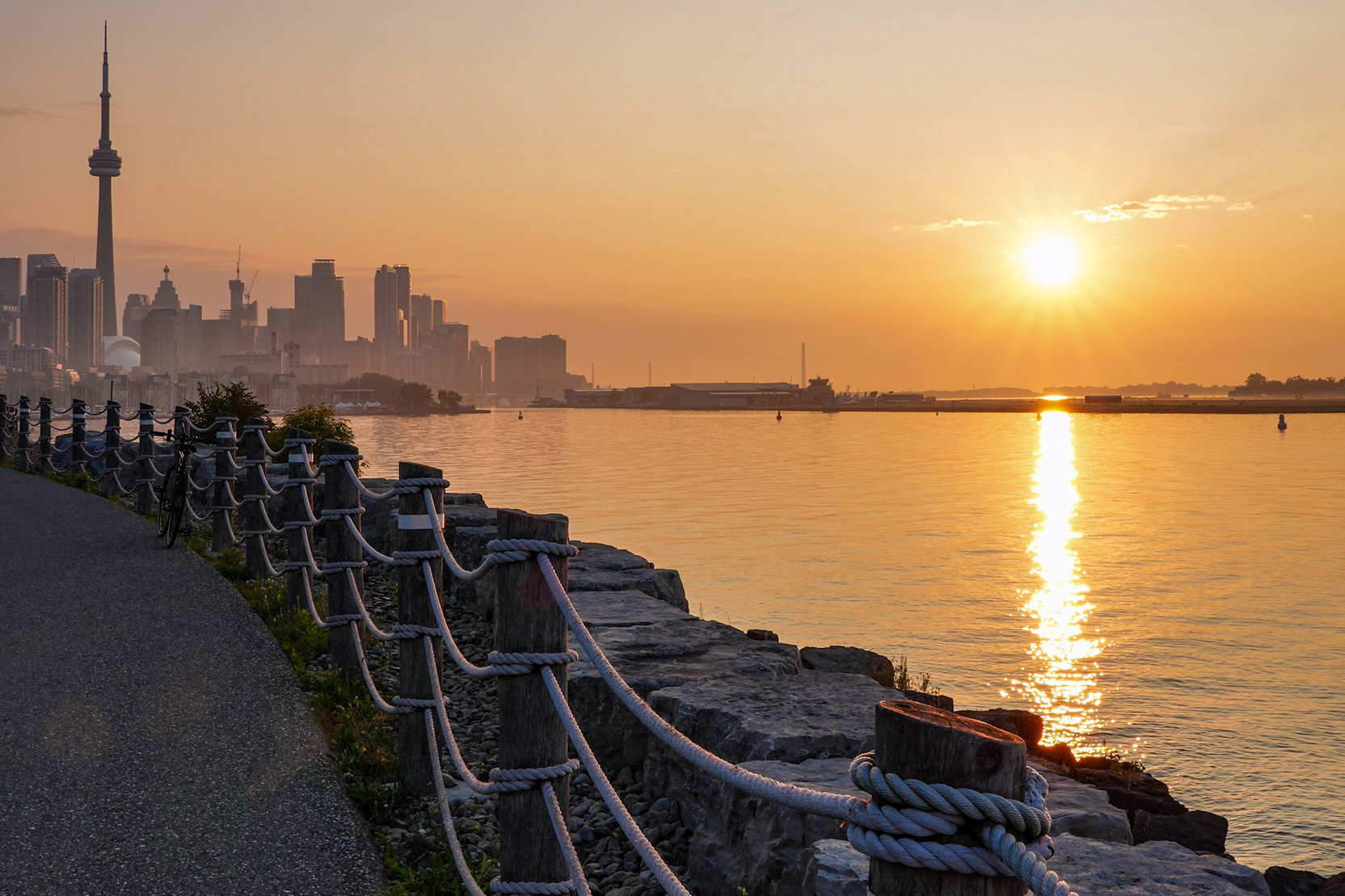 Sunset view from a trail along the lakeshore with the Toronto skyline in the background.