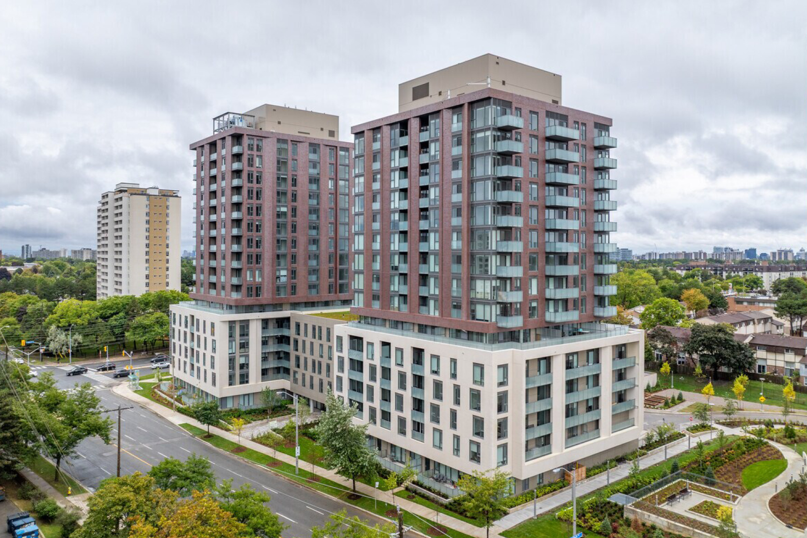 Aerial view of 3030 Pharmacy Avenue: two red-brick rental towers on a pale podium base, surrounded by landscaped gardens.