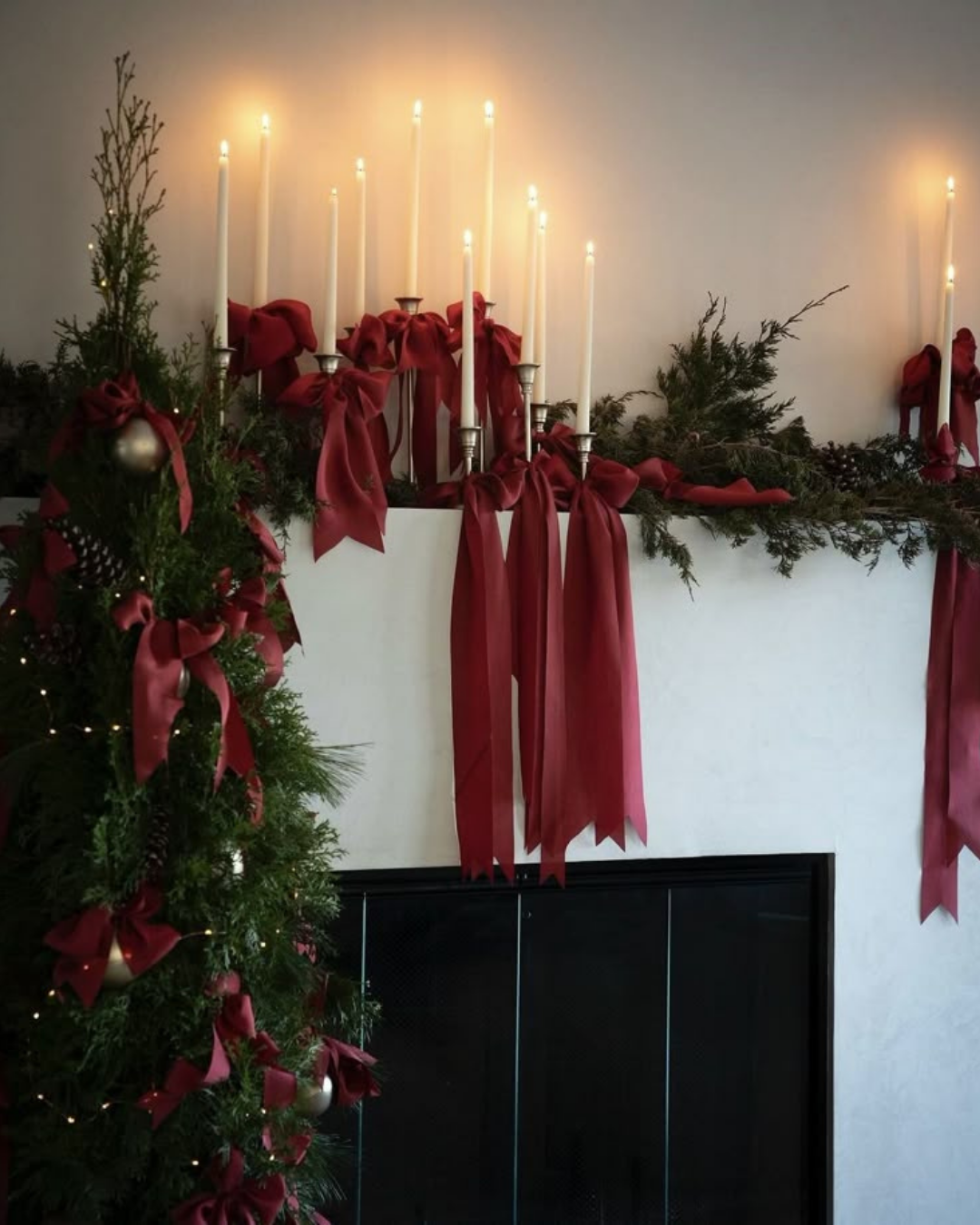 Christmas mantel decor featuring tapered candles, red ribbons, and pine garlands — a timeless and cozy touch for holiday decorating in an apartment.