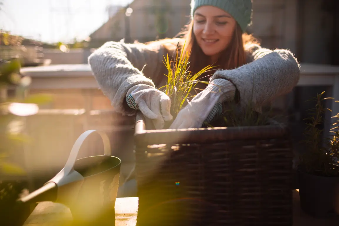 Woman on her apartment balcony tending for her plants in the winter.