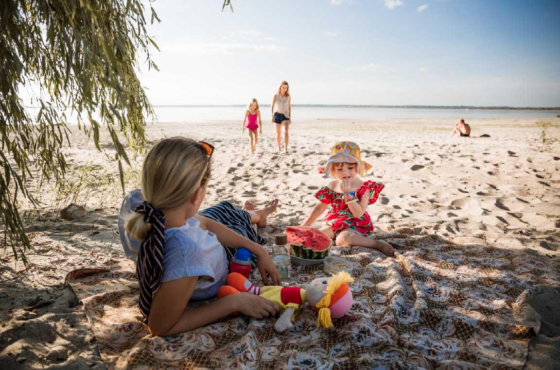 Family sits and plays together at the beach in summer