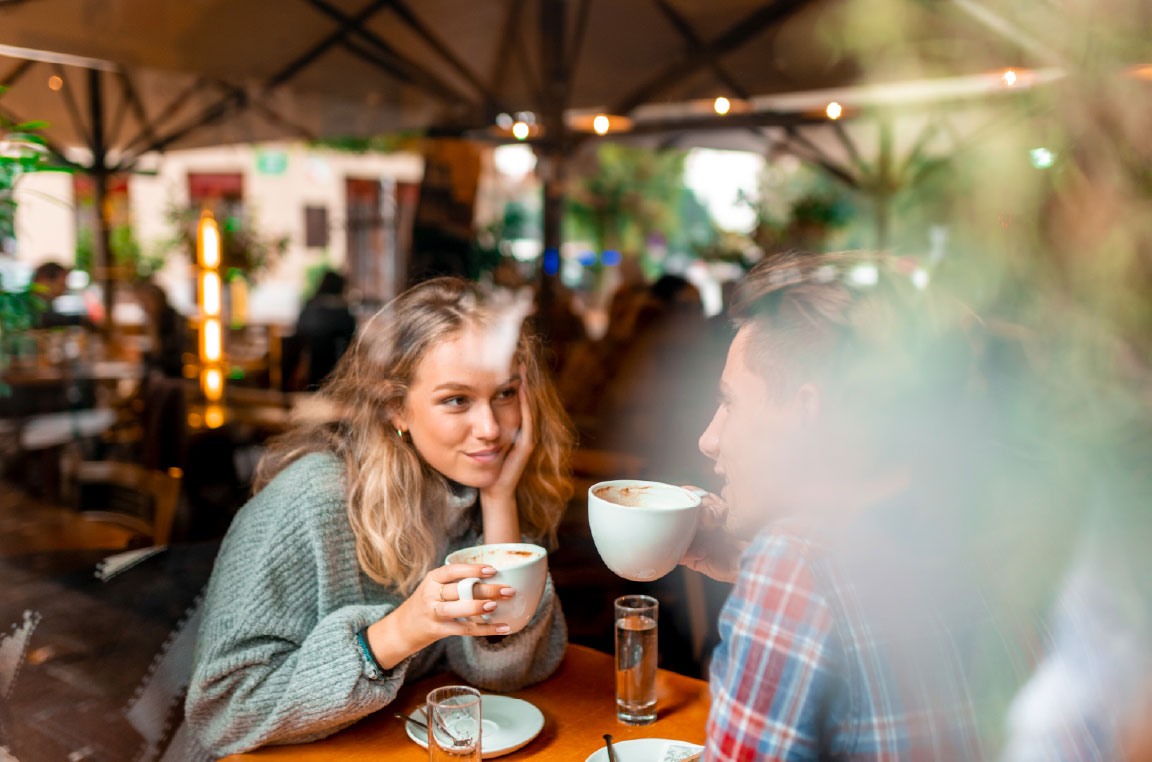 Couple sitting together at a coffee shop drinking coffee in fall