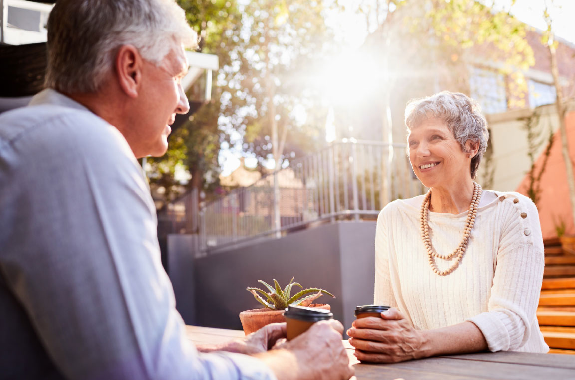 Older couple drinking coffee together at a café table in the morning
